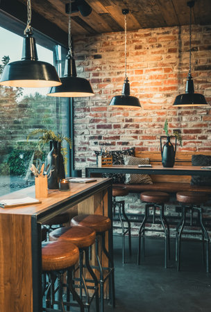 Seating area with bar tables and bar chairs in a modern cafe, industrial style with stone wall, wood and black steel, verticalの写真素材