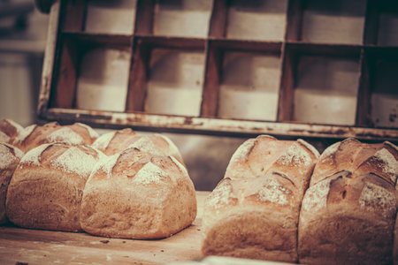 Freshly baked loaves of bread, baking pan in the backの写真素材