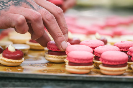 Confectioner's hands finishing pink macaronsの写真素材