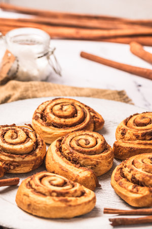 Homemade cinnamon rolls on white plate on white marble background, verticalの写真素材