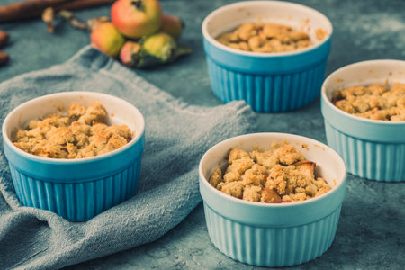Apple crumble in small blue molds on a rustic gray tableの写真素材