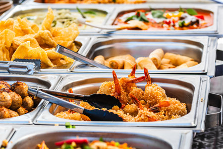 Variety of Thai dishes at a street food stand, focus on fried shrimpsの写真素材