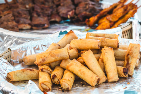 Fried Thai mini spring rolls, variety of Asian streed food dishes in the background