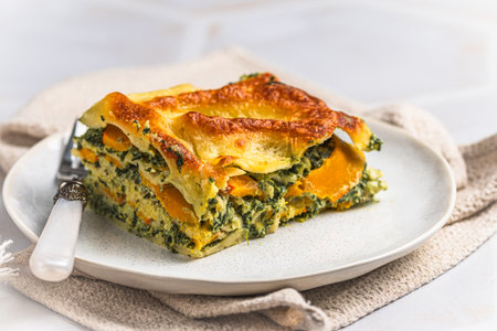 Homemade vegetarian lasagne with pumpkin, spinach and bechamel sauce, close up, copy spaceの写真素材
