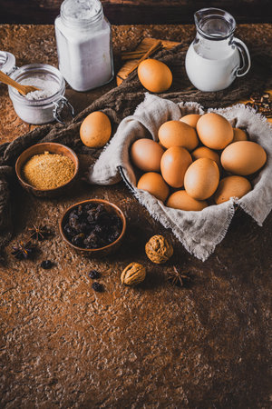 Assorted baking ingredients on wooden vintage table, in brown tone. Preparation for home baking. Vertical with space.の写真素材