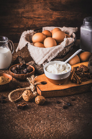 Assorted baking ingredients on wooden vintage table, brown colors. Preparation for home baking, vertical with copy spaceの写真素材