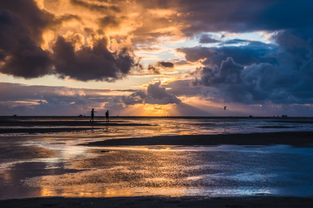 Sunset on a cloudy colorful sky over the North Sea in Denmark with high reflection in the water
