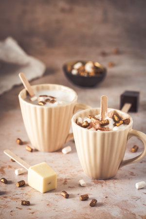 Two cups with hot chocolate, dipping sticks and marshmallows, verticalの写真素材