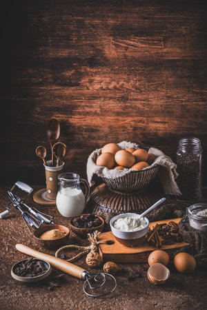 Assorted baking ingredients on rustic bronze table. Preparation for home baking. Vertical with copy...