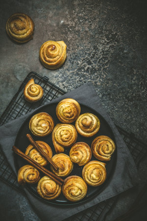 Cinnamon rolls on a black table on dark background, top view with copy spaceの写真素材