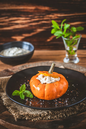 Stuffed mini pumpkin with cheese filling on wooden background, verticalの写真素材