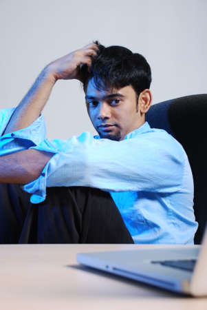 Very gloomy businessman in office environment with laptop.の写真素材
