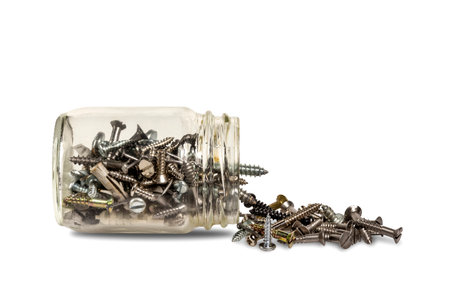 Overturned glass jar with nickel-plated screws protruding from it, on a white background.の写真素材