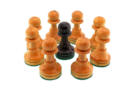Group of white chess pawns surrounding a single black pawn as a concept of racism and discrimination.の写真素材