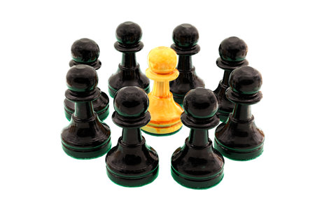 Black chess pawns surrounding a single white pawn.の写真素材