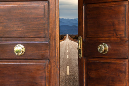 Open door with a straight road going towards the horizon. In the background a landscape of mountains. Travel and adventure concept.の写真素材
