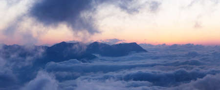Mountain landscape with clouds lying at the bottomの写真素材