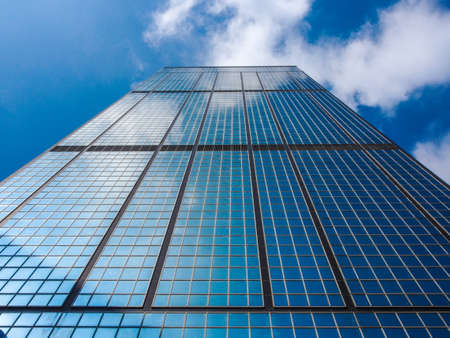 Mirror Skyscraper and Cloudy Sky Bright Backgroundの写真素材