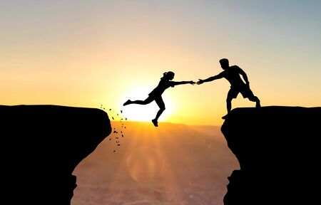 Man reaching hand to woman jumping over abyss in front of sunset.