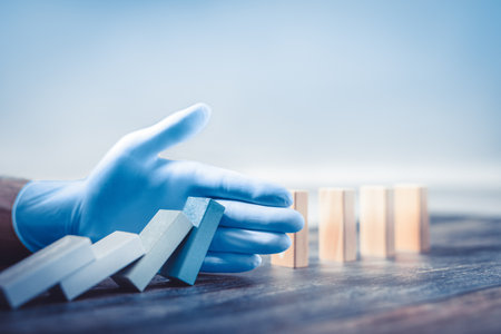 Hand with protective glove stopping domino effect.の写真素材