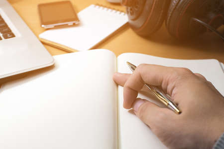 hand of working man on wood table with notebook, laptop and headphoneの写真素材