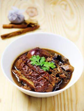 Closeup stewed pork leg in gravy soup and herb on wood tableの写真素材