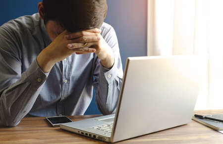 stressed businessman with laptop in office, dark tone, business conceptの写真素材