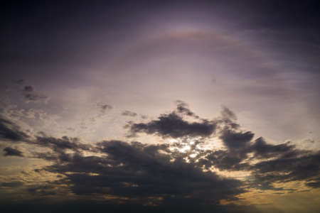 A solar halo in the evening sky among dark rain clouds.の写真素材