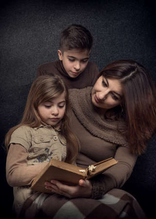 Lutsk. Ukraine. February 1, 2020; Mom reads an old book to her daughter and son. Family reading. Retro style.のeditorial素材