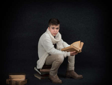 Lutsk. Ukraine. February 1, 2020; Young student student with old books on a black background. Retro style.のeditorial素材