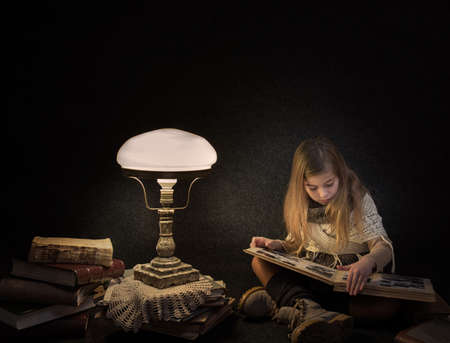 Lutsk. Ukraine. February 1, 2020; Girl with old books near a table lamp. Retro style.のeditorial素材
