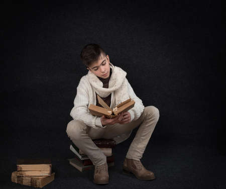 Lutsk. Ukraine. February 1, 2020; Young student student with old books on a black background. Retro style.のeditorial素材