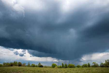 Thunderclouds over meadows and fields. The sun and jets of rain in the sky.の写真素材