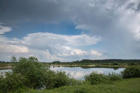 Thunderclouds over the lake. Reflection of the sky in the water.の写真素材