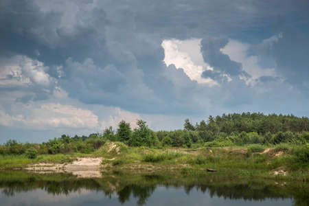Thunderclouds over the lake. Reflection of the sky in the water.
