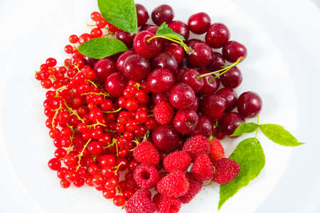 Assorted red fresh berries on a plate on a white background.の写真素材