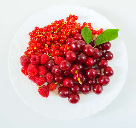 Assorted red fresh berries on a plate on a white background.の写真素材