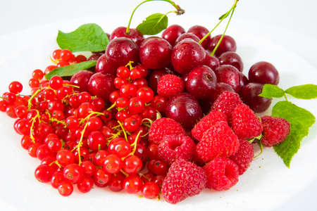 Assorted red fresh berries on a plate on a white background.の写真素材