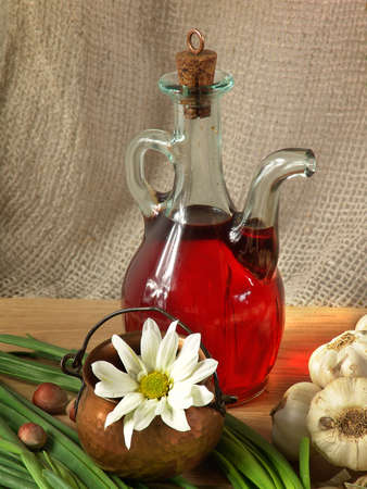 Still life with olive oil in a glass jug, a flower in a copper vessel, heads of garlic and green onions.の写真素材