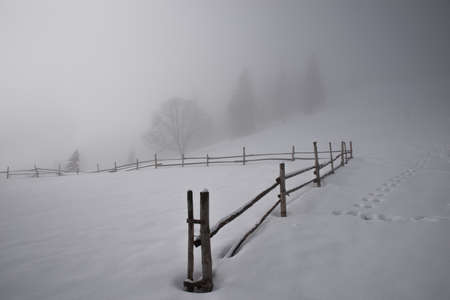 Old wooden barn high in the mountains in winter in the clouds. Thick fog. Selective focus. Blurred...