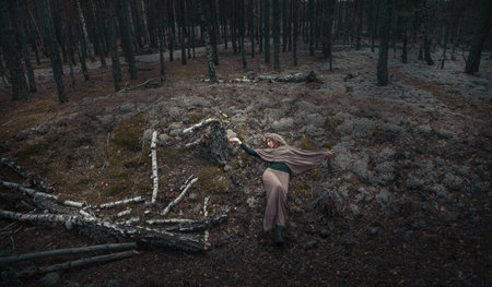 A witch woman lies on a blue moss in a dark cold forest.の写真素材