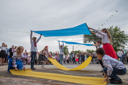Dmitrovichi. Lviv region. Ukraine. July 14, 2019; Children dance with the Ukrainian yellow-blue flag on the square at the village festival.のeditorial素材