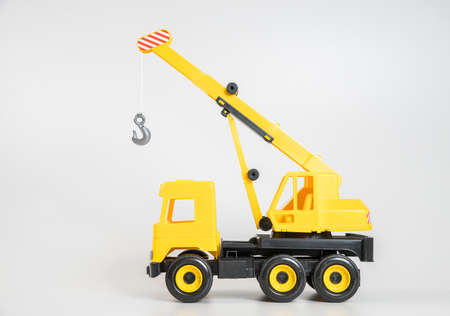 Plastic car. Toy model isolated on a white background. Yellow truck mounted crane.