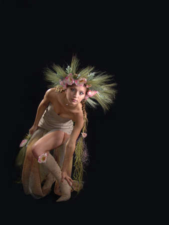Beautiful girl in a summer image and a wreath of ears of wheat on a black background.の写真素材