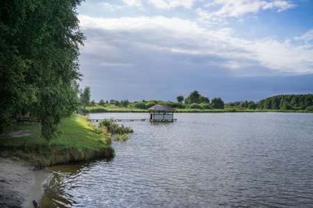 A wooden house with a thatched roof on the water surface of the lake.の写真素材