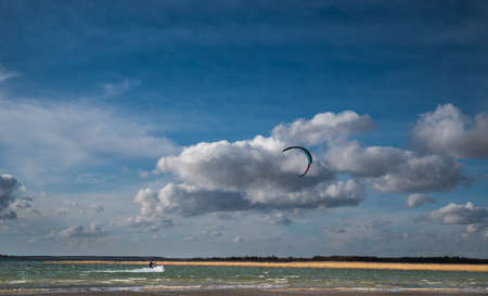 Lake Svityaz, Volyn region. Ukraine. September 5, 2019; Kitesurfing on the lake. Landscape with textured clouds and parachutes in the sky.の写真素材