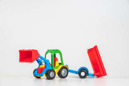 Children's toy plastic car isolated on white background. Multi-colored excavator with a trailer.