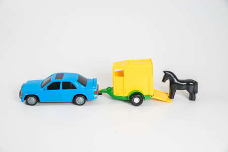 Children's toy plastic car isolated on white background. A multicolored passenger car with a horse trailer.の写真素材