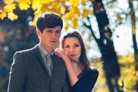 A guy and a girl in an autumn park against a background of yellow foliage. Blurred background. Selective focus.の写真素材
