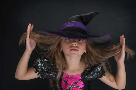 A girl dressed as a witch and a wide-brimmed hat for Halloween.